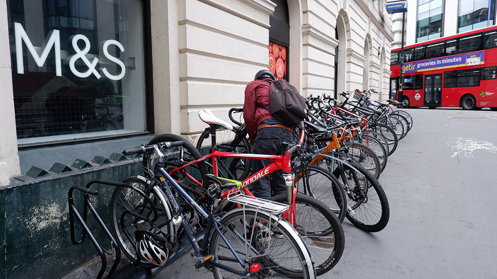 man locking bike secure cycle rack